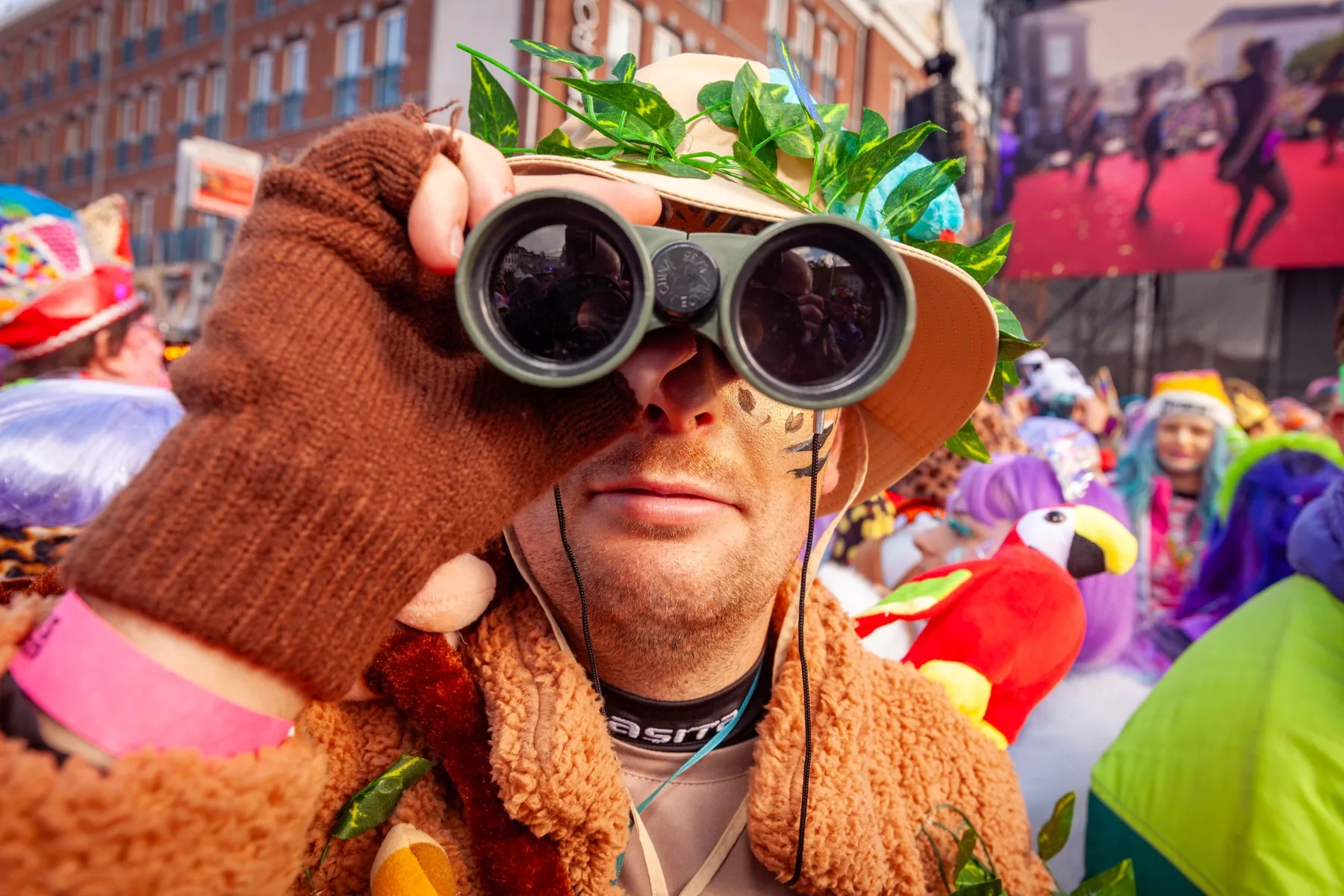 Carnavalsvierder in groen kostuum kijkt door een verrekijker